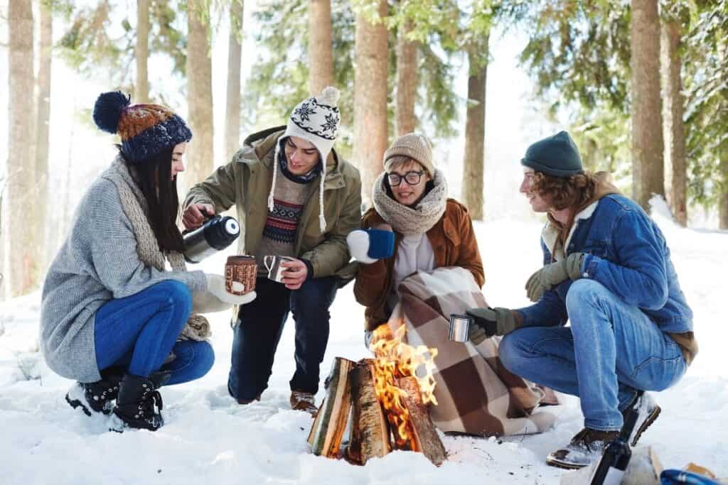 friends around campfire in snowy forest