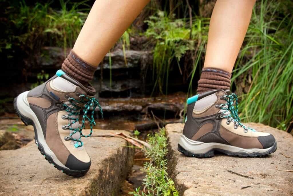 woman wearing hiking boots stepping over rocks