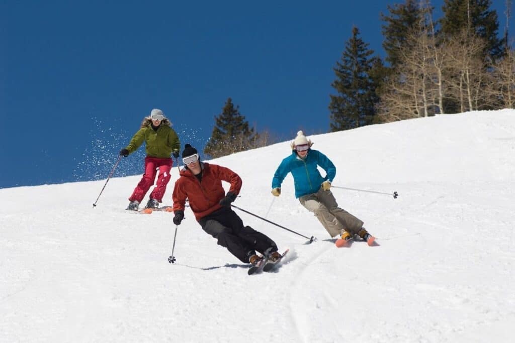 group of three skiers going downhilll