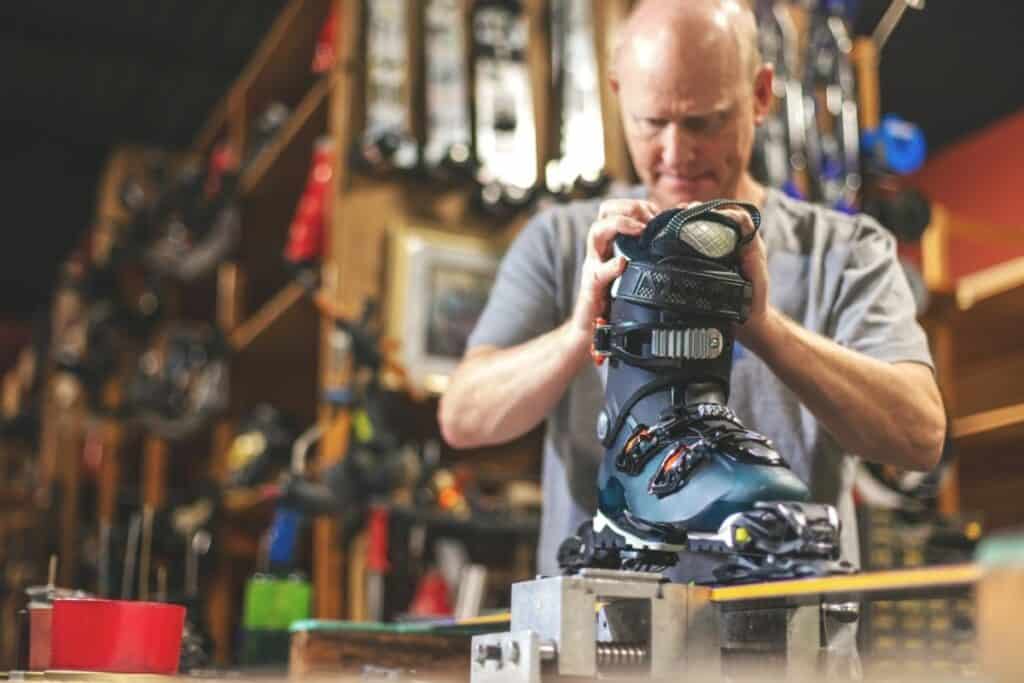 man adjusting ski binding in shop