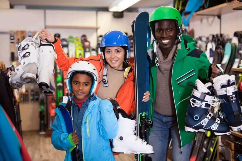 man, woman, and child holding up ski boots